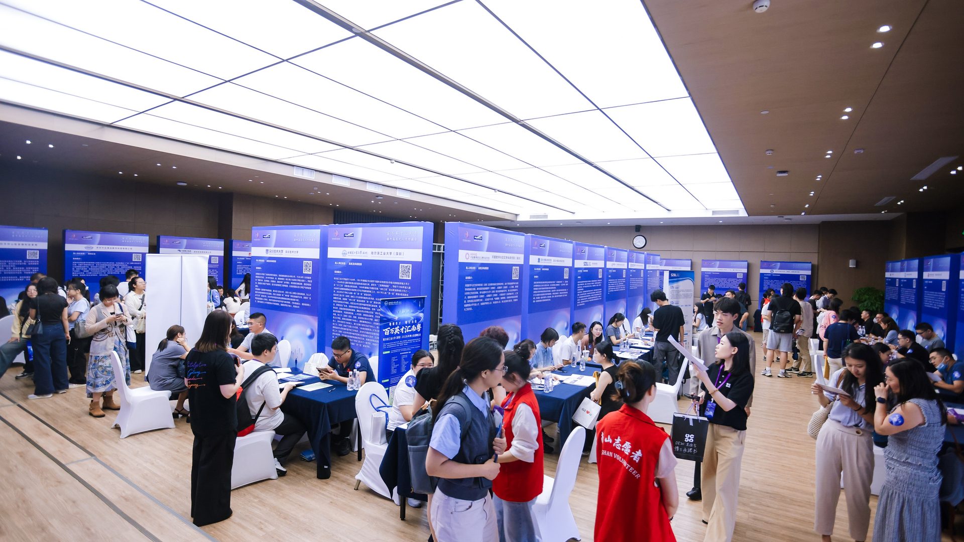 海外高层次人才对接会现场,用人单位展板前候选人洽谈,志愿者引导