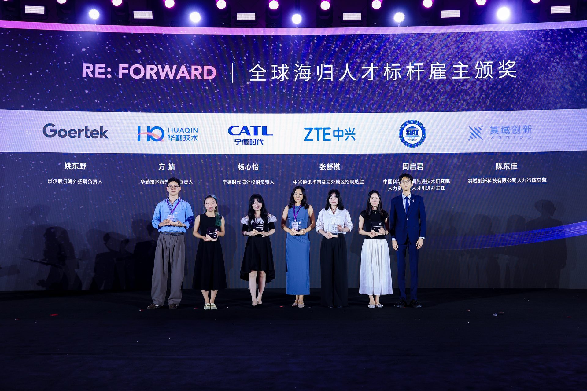 世青峰峰会「全球海归人才标杆雇主颁奖」舞台,大屏并排显示歌尔、华勤技术、宁德时代、中兴、中国科学院深圳先进技术研究院、其域创新六家单位标识,六位企业招聘负责人持奖牌站在台上