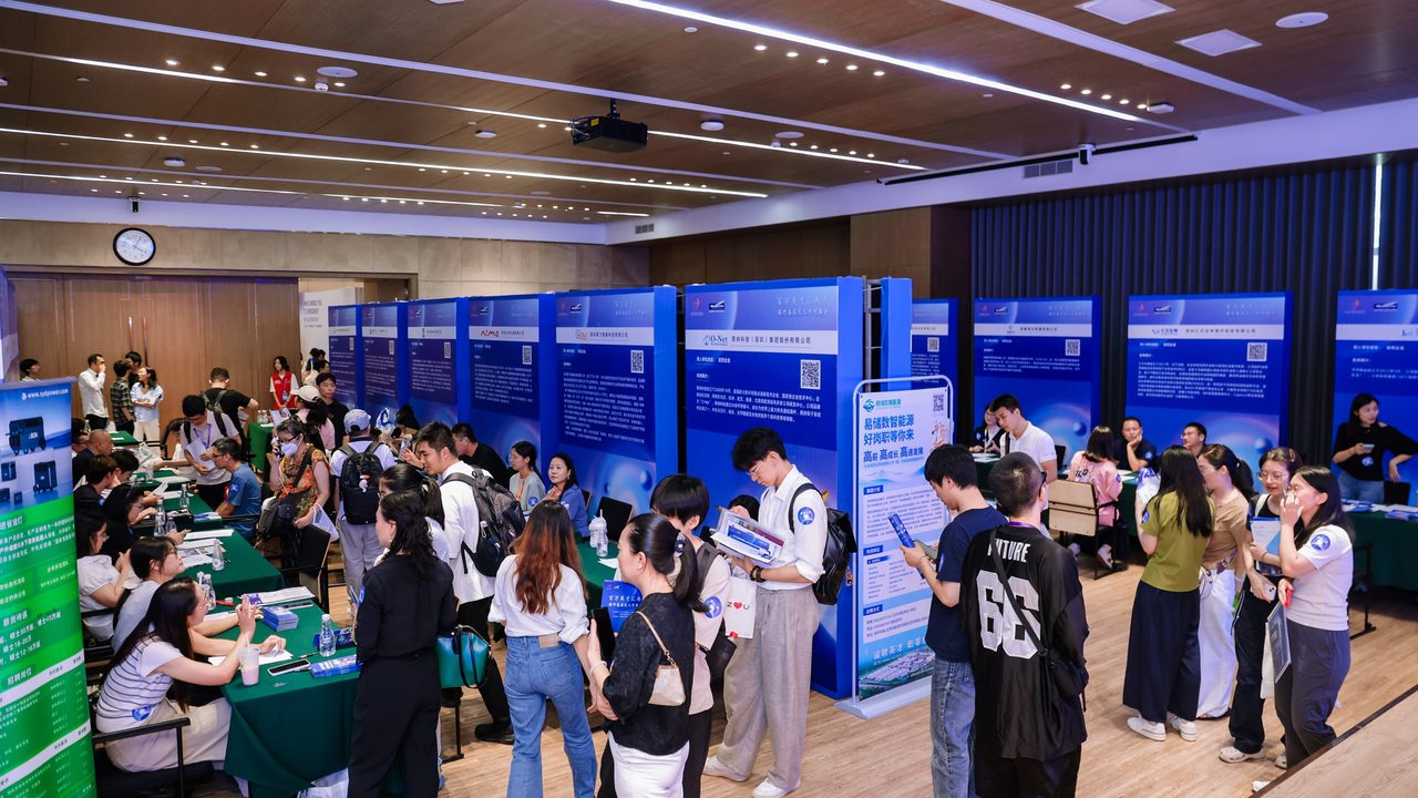 城市海外高层次人才对接会现场，用人单位展板成排，候选人在展位前咨询与登记